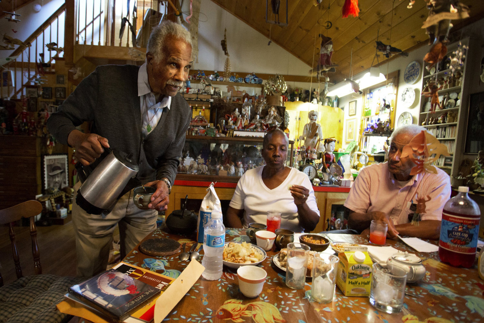 Artist Ashley Bryan, 91, pours coffee for his guests, including good friends Joyce Taylor Gibson and Roland Gibson, in the dining room of his home this summer. Photo by Gabe Souza/Staff Photographer
