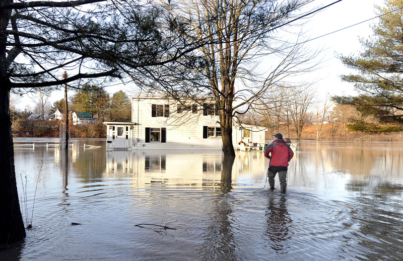 Michael Senechal of Westbrook walks through floodwaters to return to his house at 40 Lincoln St. on Friday. He said he plans to move, this being his third experience with the Presumpscot River overflowing its banks.