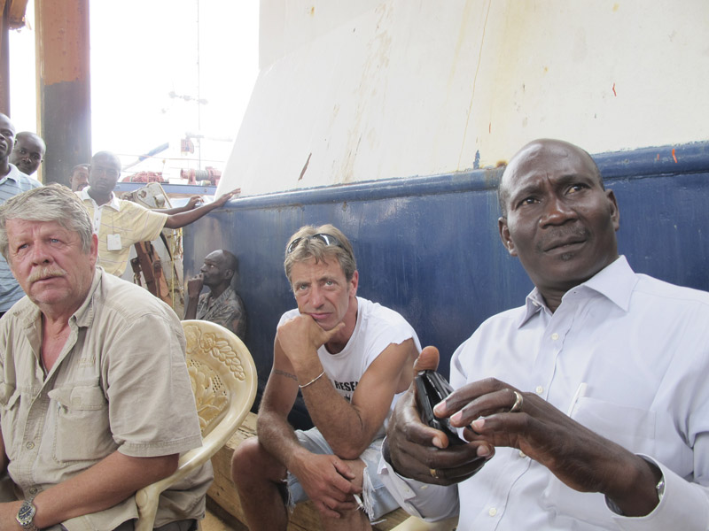 Sea Hunter owner Greg Brooks, left, and Captain Gary Esper, center, listen while Guerda Michel, CEO of Guerda Terminal Inc., speaks with dockworkers Monday afternoon at the Haitian port of Miragoane.