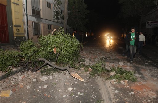 Residents walk by debris and a broken branch outside their house in Santiago.