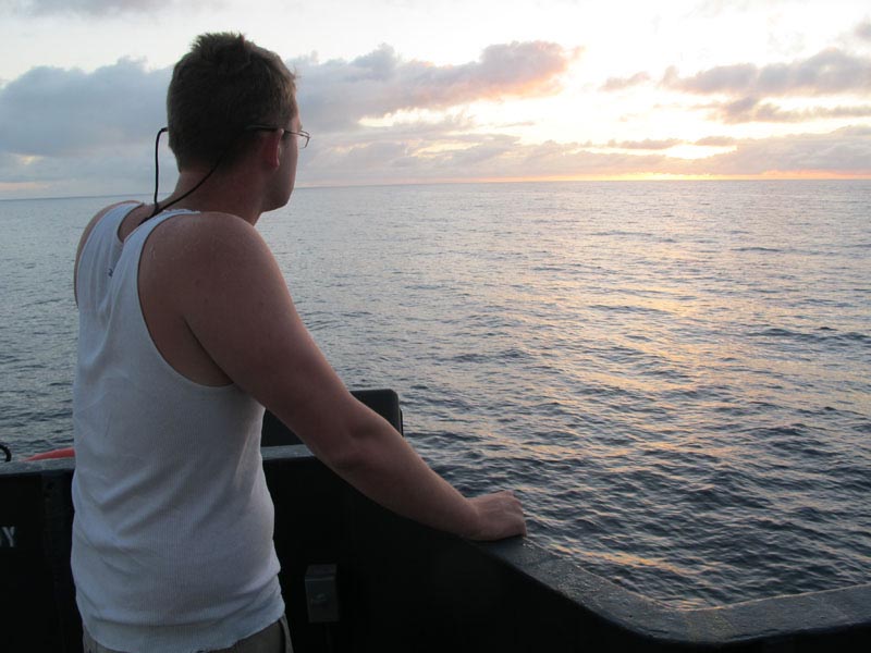 Deckhand Nick Snyer of Hopkinton, Mass., watches the sunrise as the Sea Hunter sails for Haiti this morning.