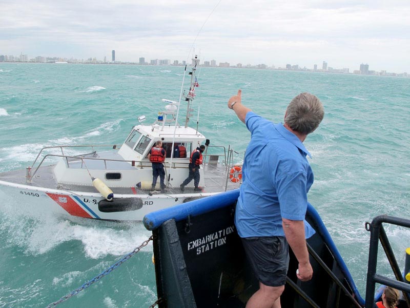 Sea Hunter owner Greg Brooks, cleared to continue his humanitarian mission to Haiti, waves farewell to Coast Guard inspectors this morning.