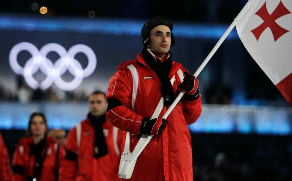 Georgias Iason Abramashvili carries his nations flag during the opening ceremonies Friday for the 2010 Winter Olympics in Vancouver. He wears a black armband in memory of countryman Nodar Kumaritashvili, who died during luge training earlier in the day.