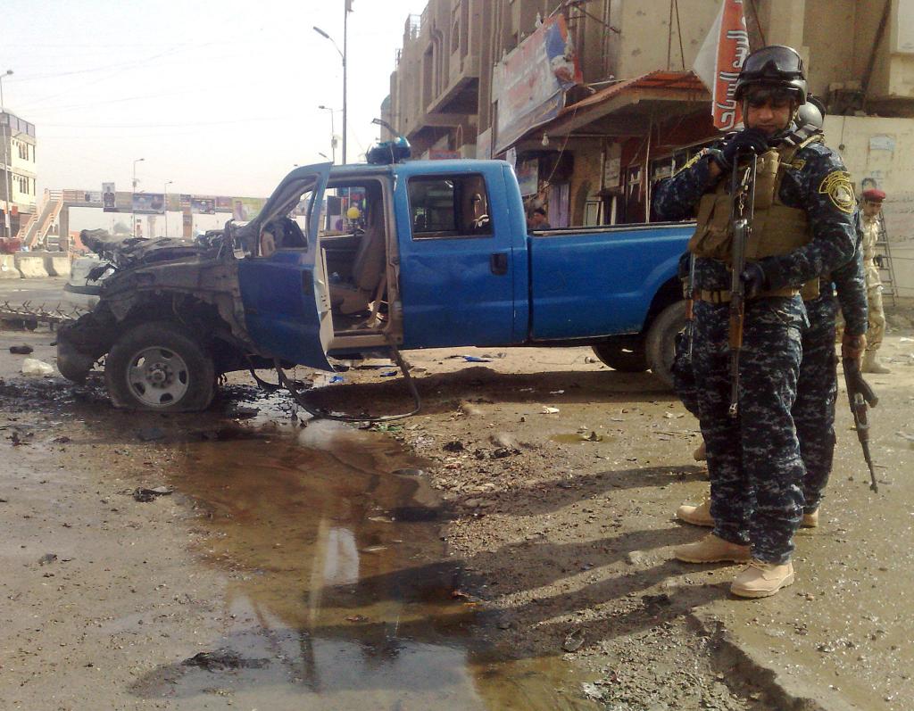 Iraqi policemen survey the scene of a suicide car bombing Thursday in Ramadi. The bomb exploded outside the gate of the main government compound, the target of daily mortar attacks during the height of the insurgency in 2005 and 2006.