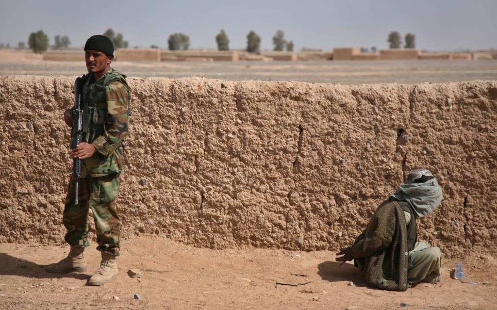 An Afghan National Army soldier stands guard as a blindfolded suspected Taliban sits with his hands tied on the ground in Marjah, Afghanistan, Thursday, Feb. 18, 2010 (AP Photo/Jerome Starkey/Pool)