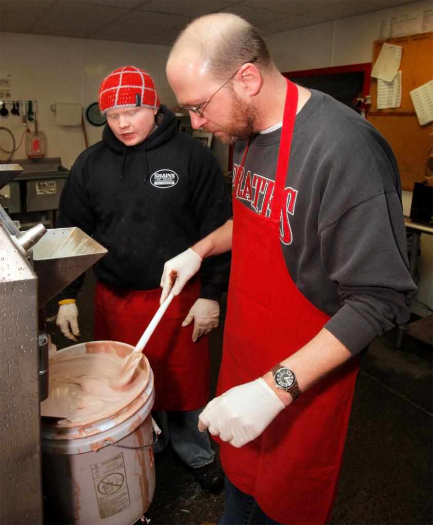 Jon Hopkins watches as Ray Routhier fills a bucket with chocolate ice cream at Shain’s of Maine in Sanford last week. A nine-gallon batch takes only 10 minutes to make, but about half a day to freeze.