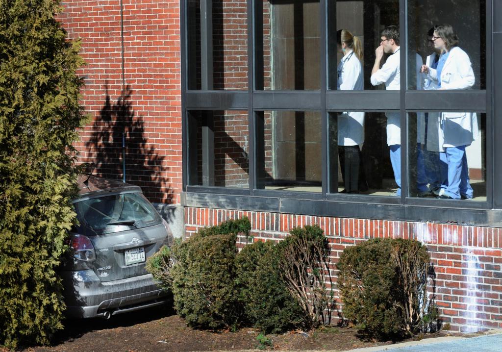 Maine Medical Center employees look at a car that crashed into a hospital building in Portland on Friday. A driver was transported to Maine Medical Center, but her condition was undetermined.