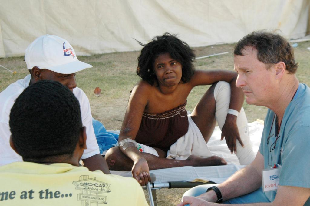 Dr. David Fitz, right, a Portland surgeon, consults with a Haitian woman and her family about the necessity of amputating her leg, at a makeshift hospital set up by the Harvard Humanitarian Initiative at an orphanage in Fond Parisien.