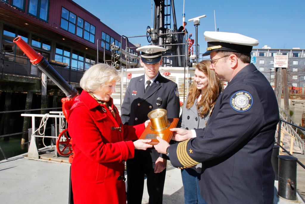 Capt. David Pendleton presents the barometer from the soon-to-be-retired City of Portland III fireboat to Deborah Gray, who christened the boat in 1959. With them are Valerie Pendleton, 14, who christened the new Portland fireboat, and Portland Fire Chief Frederick LaMontagne.