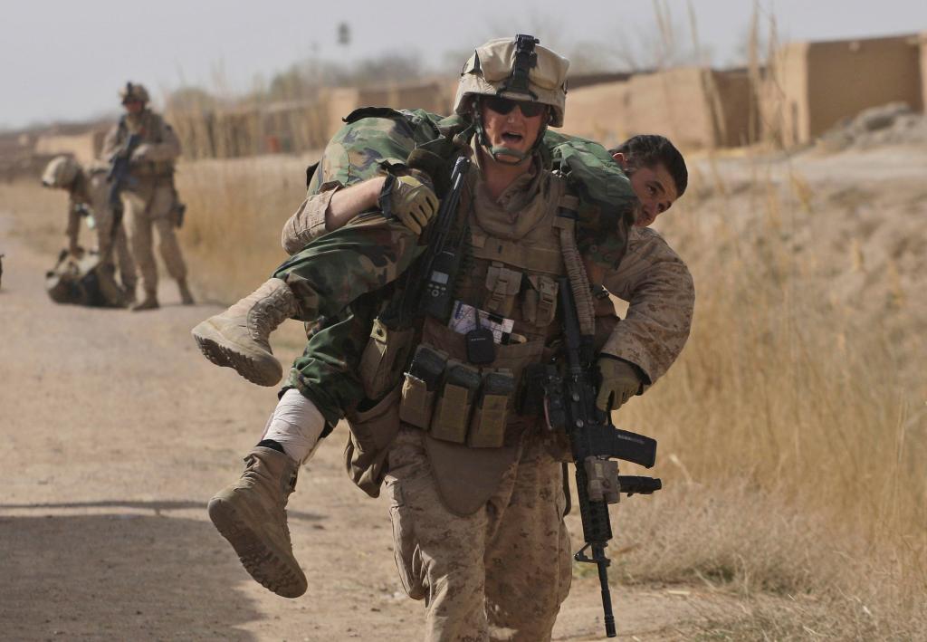 U.S. Marine Lt. Scott Holub of Pasadena, Md., carries an Afghan National Army soldier who was shot in the lower leg during a battle with the Taliban in Marjah on Saturday.