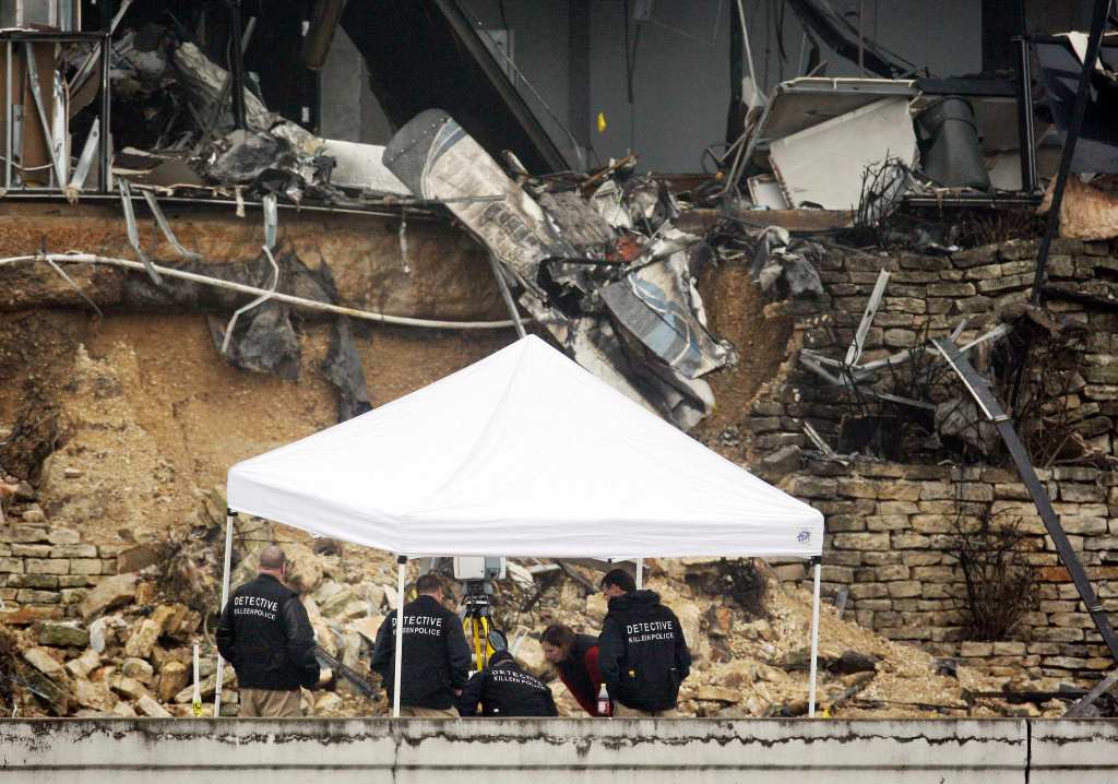Police huddle beneath a tent in front of plane wreckage in an IRS building in Austin, Texas. Authorities say Joseph Stack crashed the plane because he felt the IRS had ruined his life.