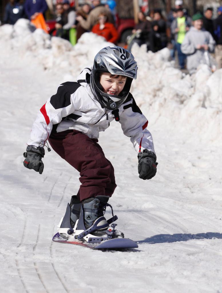 Camden Kelly, 7, of Saco snowboards on the sliding hill built on Old Orchard Street with trucked-in snow.