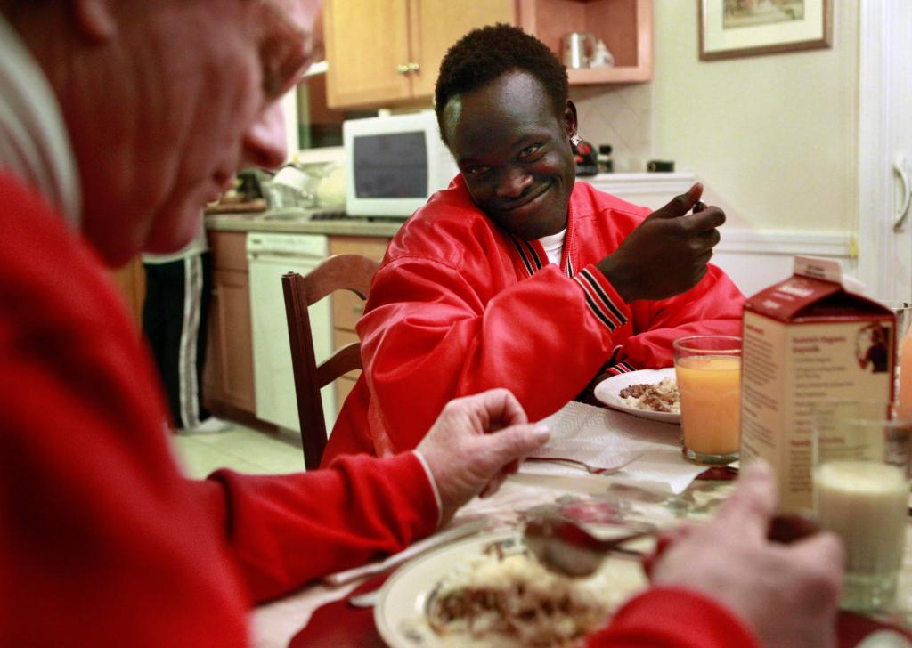 Sudanese war refugee Madhel Majok, 17, now a high school student in Massachusetts, chats with foster parent Paul Boulanger over dinner at their home in Holliston.