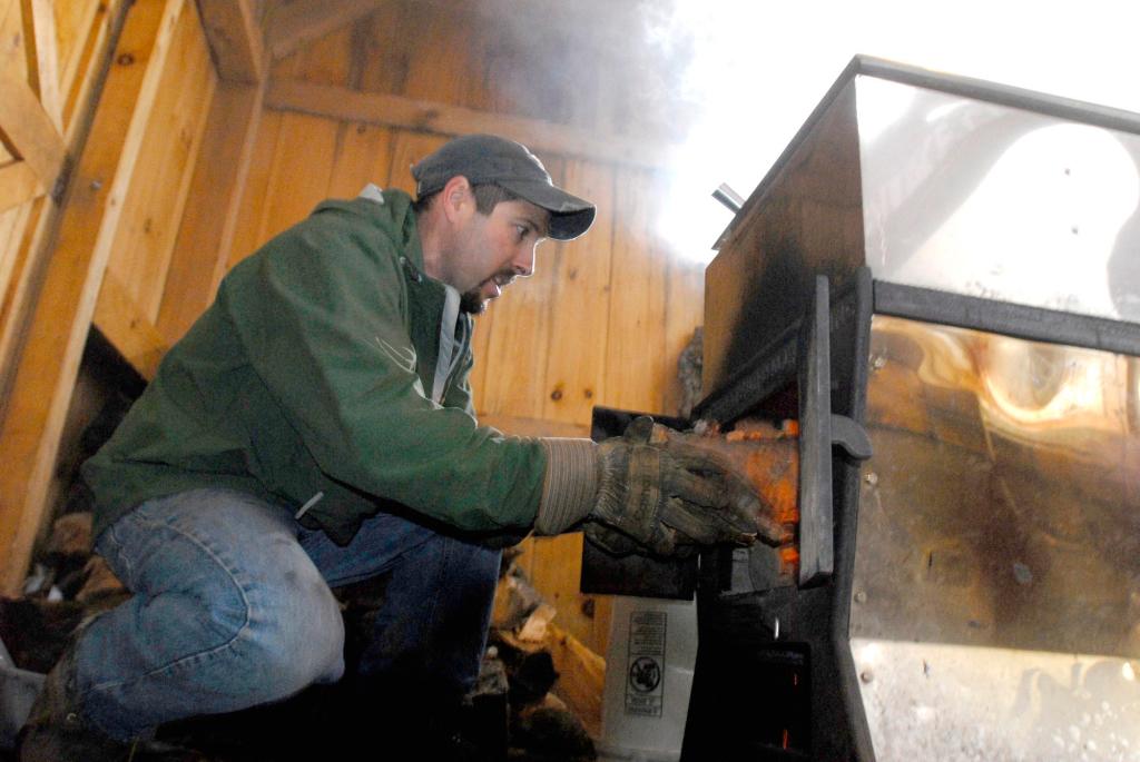 Keith Harris adds wood to the fire in the evaporator that boils the sap.