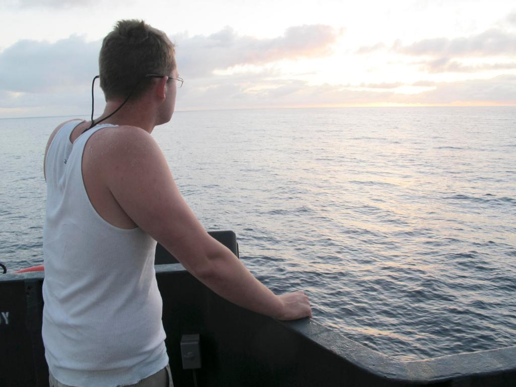Aboard the Sea Hunter, deckhand Nick Snyer of Hopkinton, Mass., watches the sun rise Tuesday as the Maine vessel sails toward Haiti.