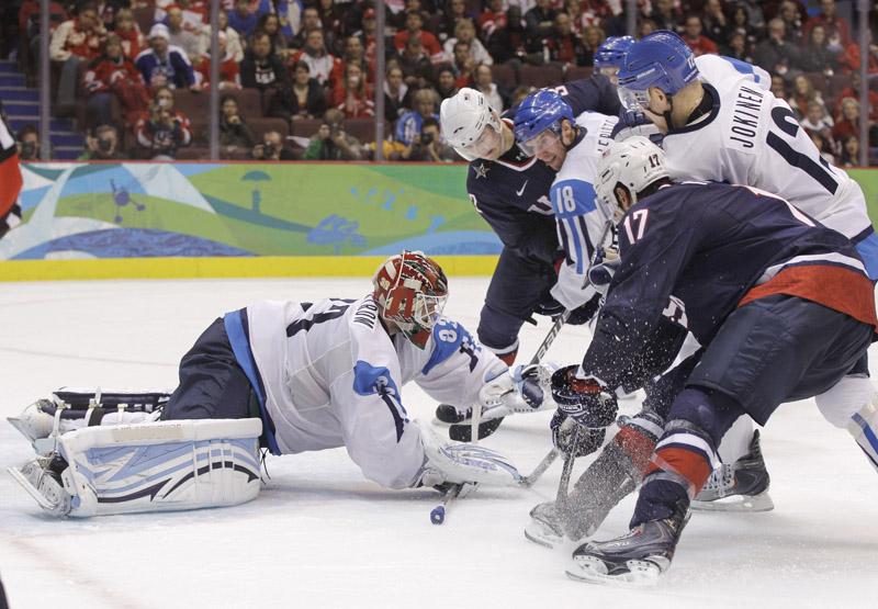 Finland goalie Niklas Backstrom covers the pucks as players from both teams look for a rebound Friday in their men’s hockey semifinal. The U.S. won 6-1 and will play for the gold medal on Sunday.