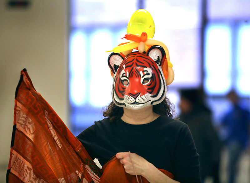 Phyl Rubinstein of North Yarmouth, wearing a tiger mask, helps with the food.