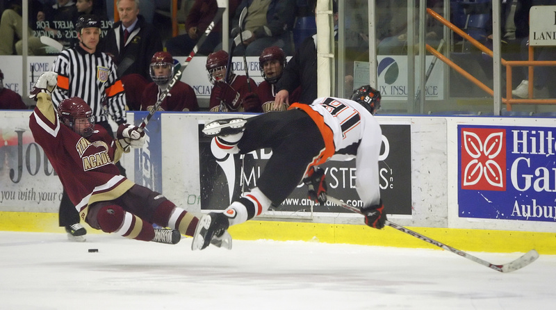 Brandon Veilleux of Thornton Academy, left, and Trevor Fleurent of Biddeford head to the ice after colliding Tuesday night as the puck continues to roll past them. Biddeford won the Western Class A title with a 3-0 victory.