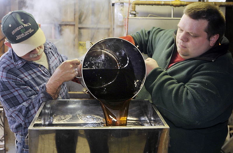 Steven McKenney and son, Ben McKenney, pour condensed maple syrup into the canning machine that will reheat, filter and prepare for bottling some of this season’s syrup at Grandpa Joe’s Sugar House.