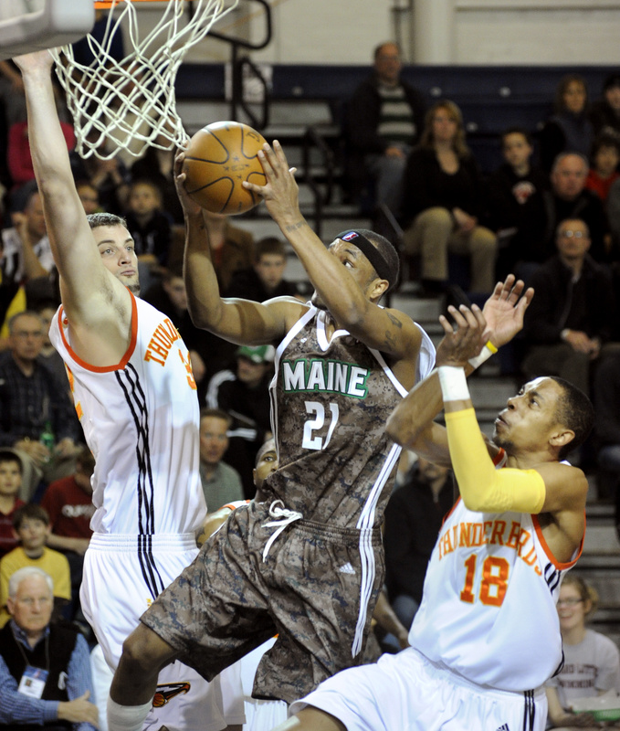 Maurice Ager of the Maine Red Claws drives between Sasha Cuic, left, and Trey Gilder of the Albuquerque Thunderbirds during the Red Claws’ 128-111 victory Friday night at the Portland Expo.
