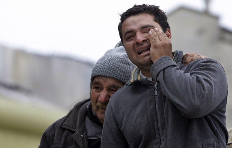 Relatives of earthquake victims cry outside a destroyed building Sunday in Concepcion, Chile’s second-largest city.
