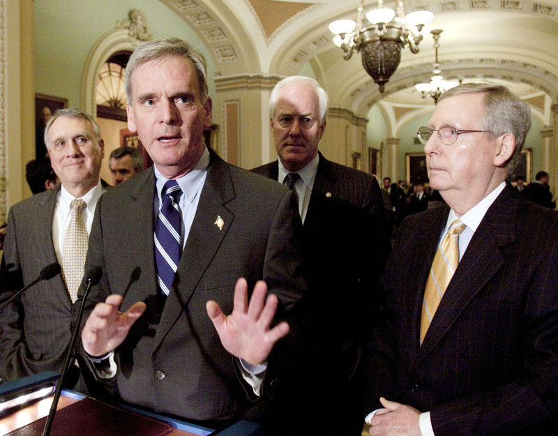 Sen. Judd Gregg, R-N.H., second from left, speaks to reporters on Capitol Hill in Washington Tuesday. Gregg wants a vote on his amendment to plow savings from Medicare cuts back into the health care program for seniors, instead of being used to expand coverage to the uninsured.