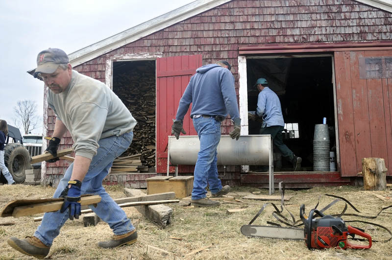 PACKING UP: Jim Gilbert, left, collects slabs of firewood Sunday in front of Mark Fenderson's sugar shack in Whitefield. Several of Fenderson's friends helped him clean and pack up the shack after only making syrup for seven days this years. "It was a pretty short season," Fenderson said.