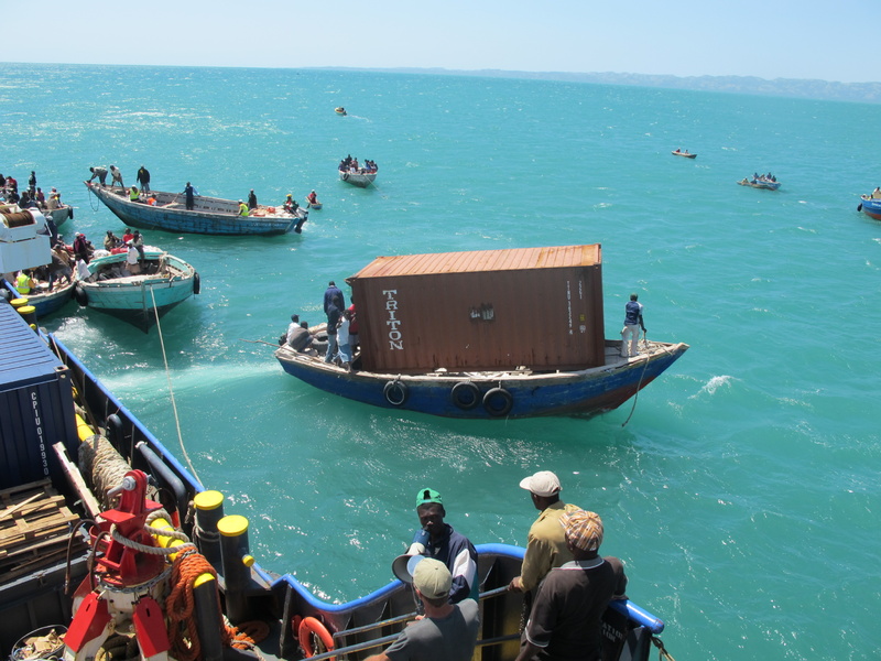 A Haitian boat leaves the Sea Hunter on Sunday with a 20-foot shipping container and heads for the dock in Les Cayes, Haiti. All 10 of the empty containers, which will be converted into buildings, made it safely ashore.