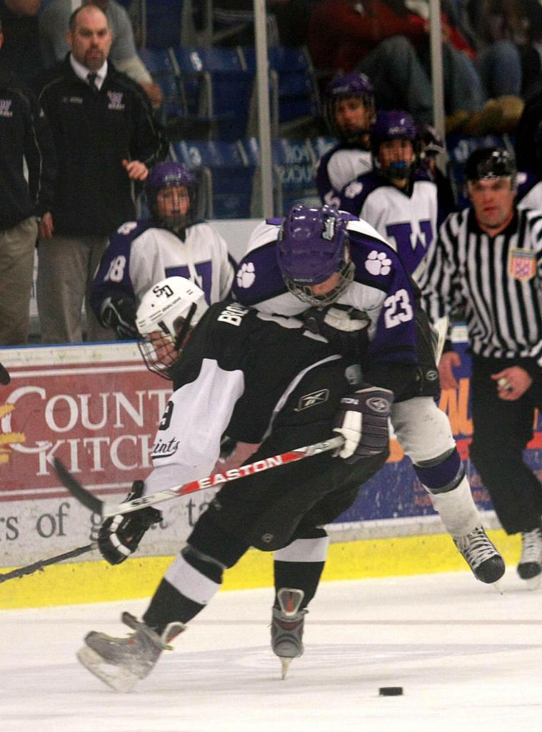 Cam Brown of St. Dominic checks Tim Locke of Waterville off the puck Tuesday night during Waterville’s 3-2 victory in the Eastern Class A final at Lewiston. Waterville is the defending state Class A champion.