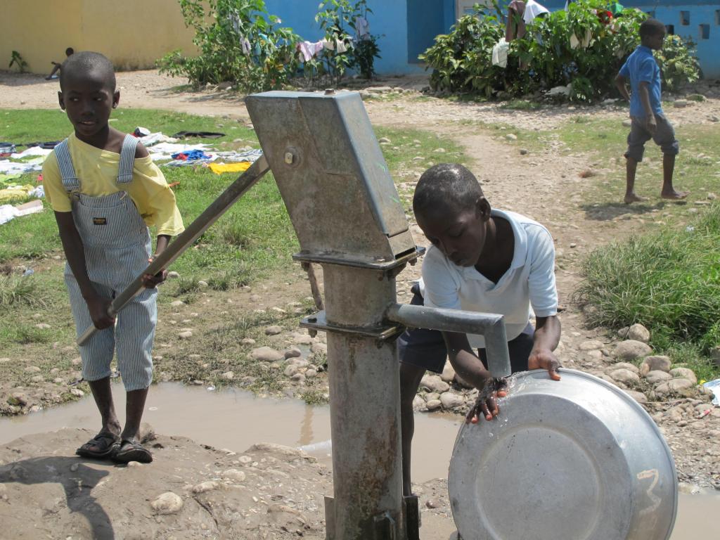 Orphan boys pump water, left, to clean a washing tub at Hope Village in Les Cayes. Almost half of the relief supplies aboard the Maine ship Sea Hunter are being delivered this weekend to the orphanage and community. assistance program.