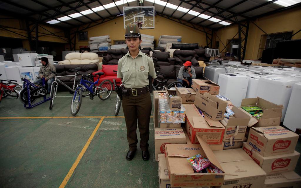 A police officer stands in front of hundreds of items either returned by looters or recovered by the police at a police station in Concepcion, Chile, on Sunday. Looting started after an 8.8-magnitude earthquake struck central Chile on Feb. 27.