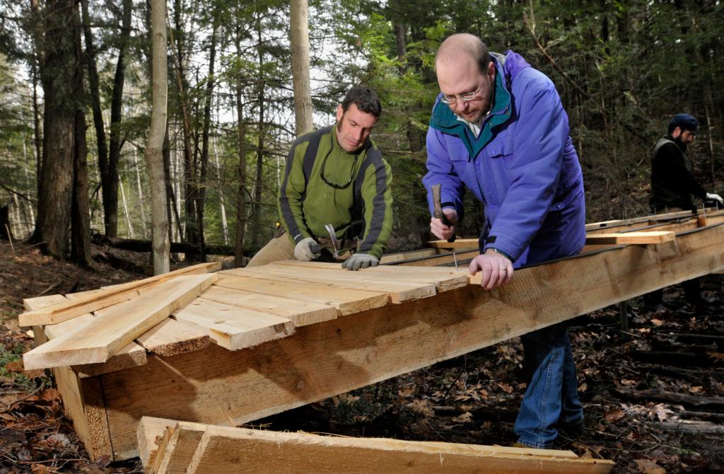 Reporter Ray Routhier learns trail management and small bridge building last week from Jaime Parker, trails manager, and his foreman, Charlie Baldwin, right, as they create a new trail in the Fore River Sanctuary for the season.