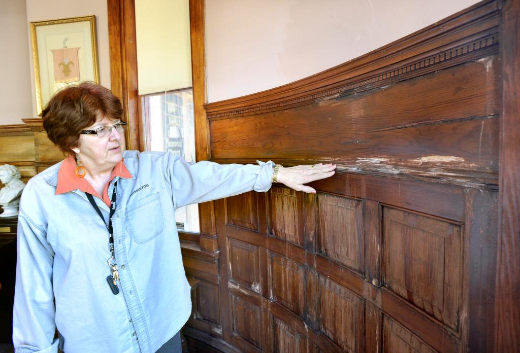 Karen Valley, director of Walker Memorial Library, points to water-damaged paneling inside the building’s north wall. A consultant has found asbestos and mold in the Westbrook facility.