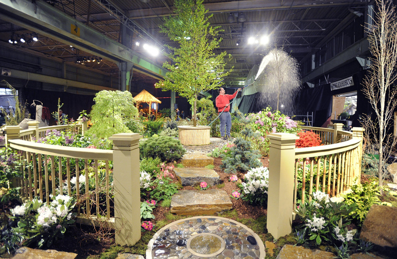 Tom Estabrook of Estabrook Farm in Yarmouth waters his creation Tuesday as he and other workers complete exhibits for the Portland Flower Show at the Portland Company Complex, 58 Fore St. Tickets for tonight’s opening gala are $40; the show runs through Sunday.
