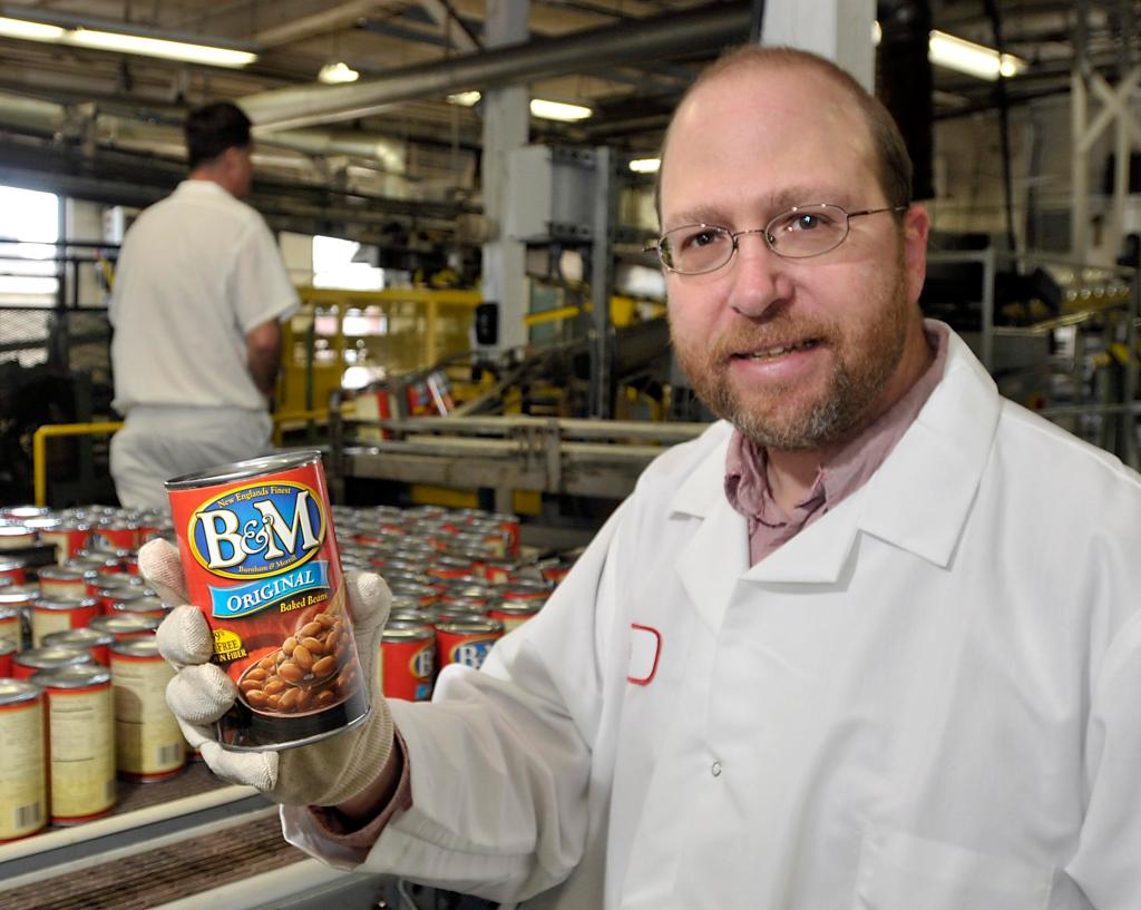 Ray Routhier holds a can of B&M Baked Beans, ready for the stores. B&M employees take pride in the fact that their product is baked, noting that some rivals just steam their beans.