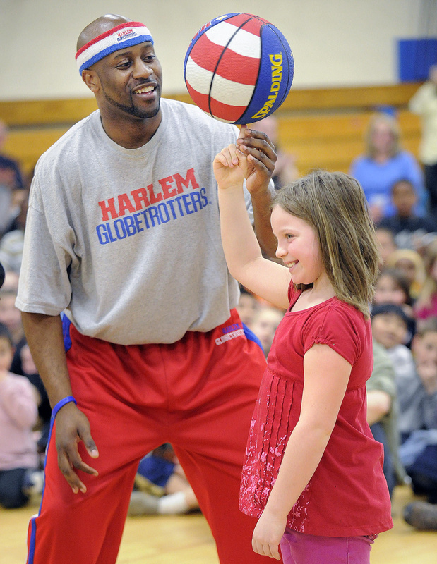 On a visit last Friday to Reiche Elementary, Hot Shot Branch of the Globetrotters gives Malea Cross-Robertson a lesson on the old spinning ball routine.