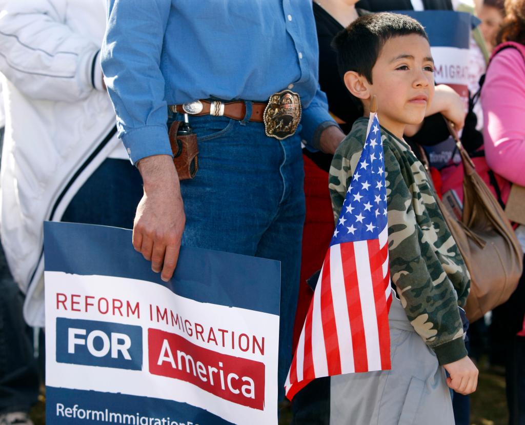 Eight-year-old Adrian Gomez carries an American flag during a rally in Denver on Sunday to spur lawmakers to reform immigration policies. The rally was part of a nationwide effort to bring attention to immigration issues.