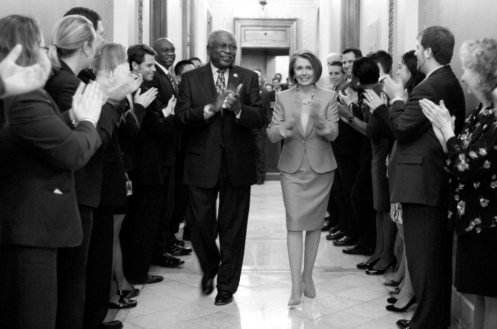 Speaker Nancy Pelosi of California is applauded as she walks with Rep. James Clyburn, D-S.C., after the House passed health care reform Sunday.