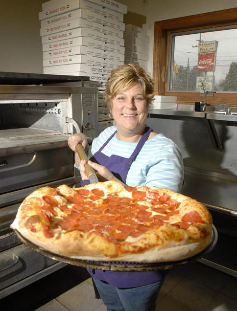 Darlene Walsh, owner of 8-Corners Pizza in Scarborough, displays a freshly made pepperoni pizza.