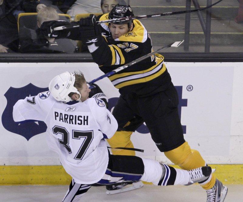 Steve Begin of the Bruins checks Tampa Bay’s Mark Parrish during Thursday’s game in Boston. The Bruins lost 5-3 despite outshooting the Lightning 50-18.