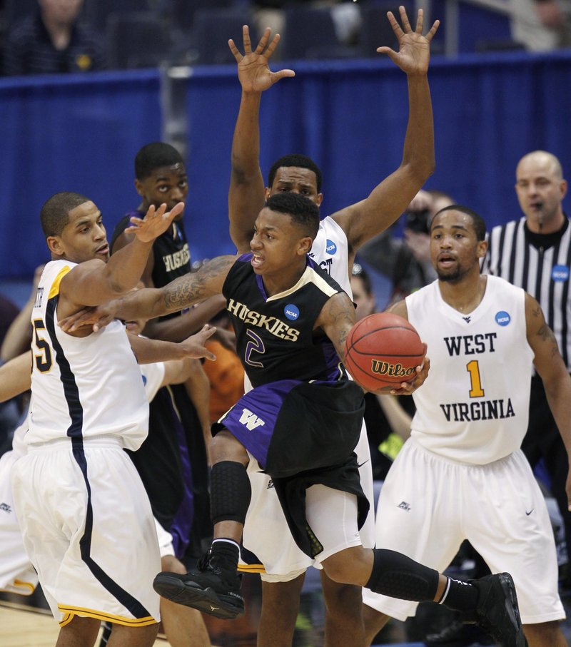 Isaiah Thomas of Washington looks to pass Thursday night as the West Virginia defense moves in during West Virginia’s 69-56 victory in an East Regional semifinal.