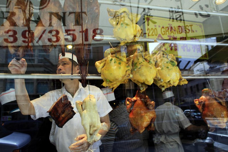 A worker at a restaurant in the Chinatown neighborhood of Manhattan reaches for a pungent roasted duck hanging in the window Friday. Rockefeller University researchers spent five years creating a “smell demography” of metropolitan New York City to sniff out what New Yorkers think is noxious or nice.