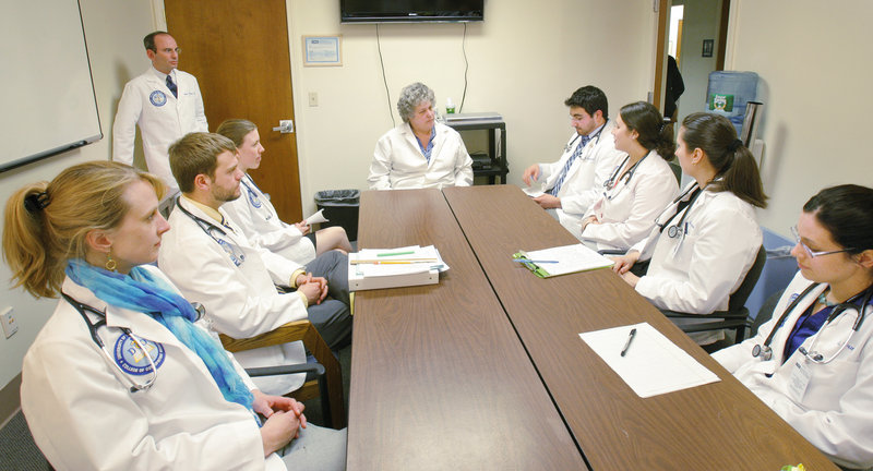 Elisabeth DelPrete, D.O., center, chair of the University of New England’s department of family medicine, meets last week with first-year medical students to discuss the mock physicals in which they had just participated. Fifteen percent of Maine’s primary care doctors are UNE graduates with a doctor of osteopathy degree, said the medical school’s dean.