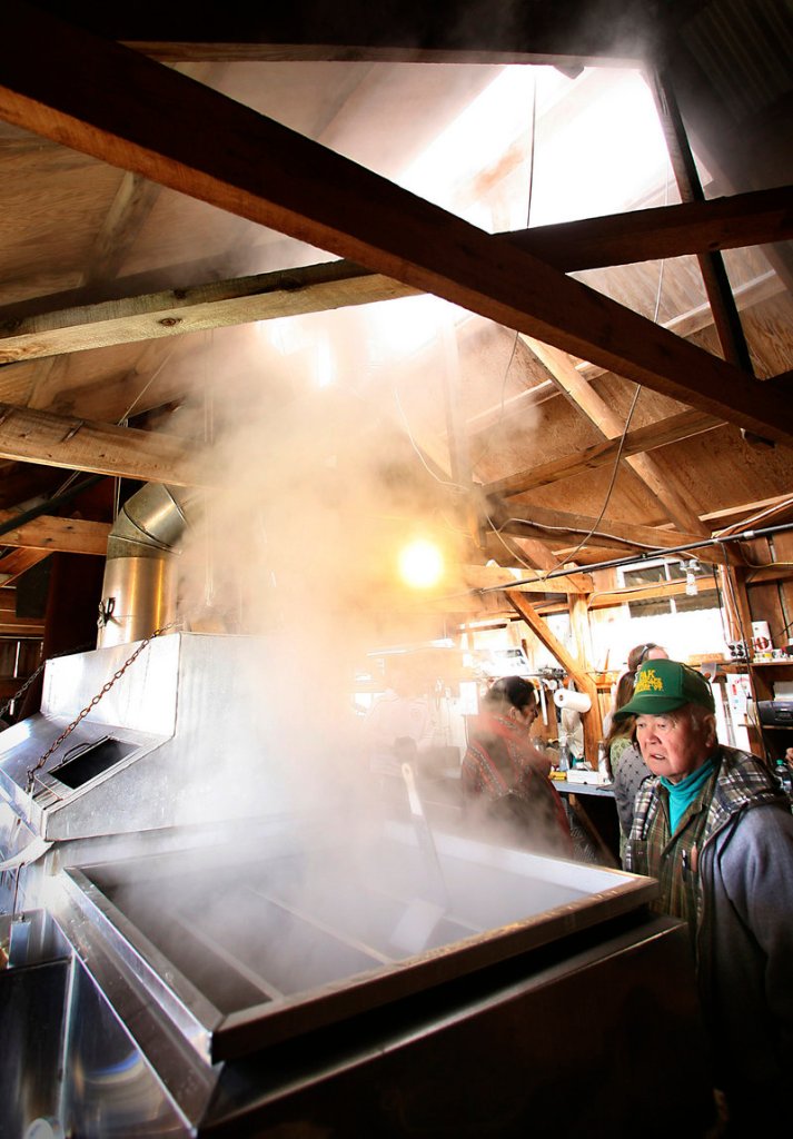 Jimmy Pak of Biddeford watches on Saturday as sap is boiled in the evaporator at Cole Farm. The boiling evaporates the water in the sap, leaving the syrup the farm sells, at left.