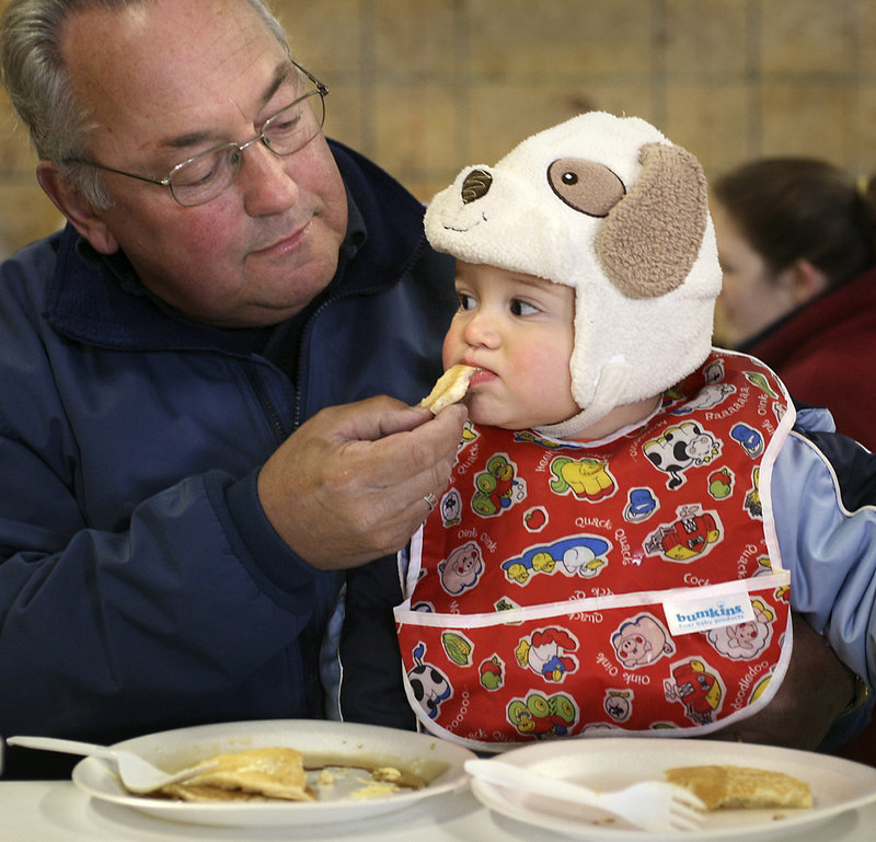 Malcolm Graffman of Saco feeds a piece of pancake to his 10-month-old grandson Quinn Purvizat. About 320 visitors tried Cole Farm’s maple syrup on buttermilk pancakes Saturday.