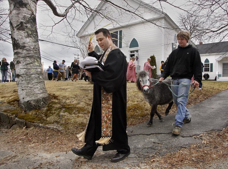The Rev. Derek White leads a procession that includes Rosie, a pony led by Nathan Cole, at the First Congregational Church in Kennebunkport on Sunday. Children at the church suggested the new Palm Sunday observance.