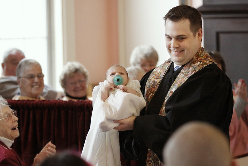 The Rev. Derek White shows his 6-week-old son, Silas, to the congregation after baptizing him at the First Congregational Church in Kennebunkport on Palm Sunday.