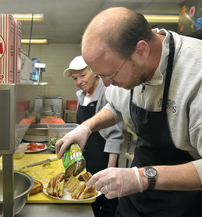 Under the watchful eye of Judy Levesque, Ray Routhier adds chips to the plate as he makes club sandwiches at the Cape Elizabeth Middle School cafeteria.