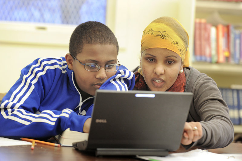 Nadar Mohamud, right, an AmeriCorps volunteer who grew up in the Kennedy Park neighborhood, helps Portland High School freshman Abdi Mohamed work on a report he is writing about Acadia National Park at Kennedy Park's study center.