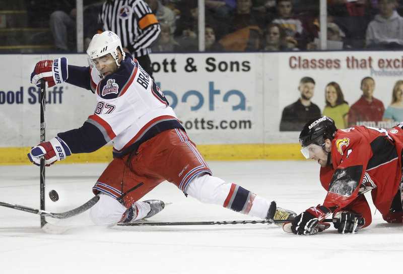 Drew Schiestel, right, of the Pirates dives in attempt to knock the puck away from Donald Brashear during Portland's 3-2 win Sunday over the Hartford Wolf Pack at the Cumberland County Civic Center.